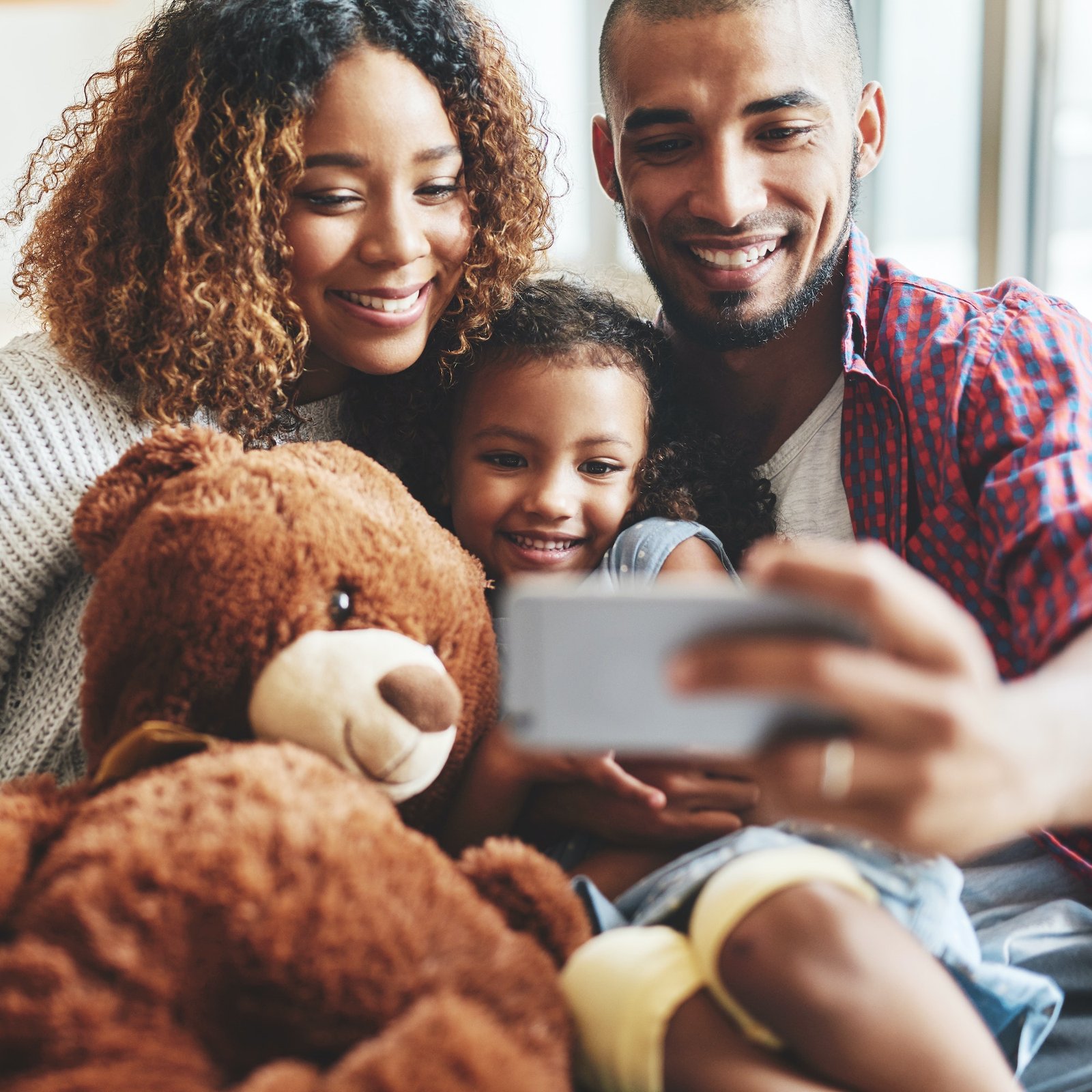 Cropped shot of a happy young family of three taking selfies together in their living room at home